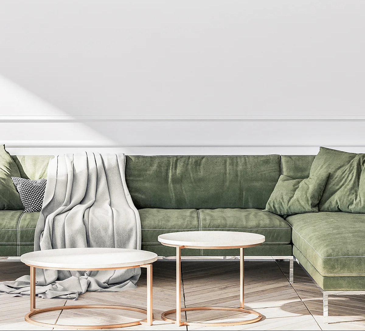 Green sectional sofa with a blanket and two coffee tables in a minimalistic room.
